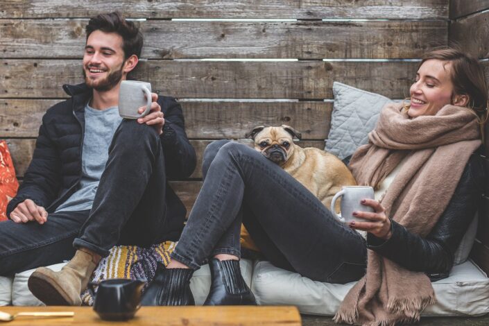 Young couple celebrate the weekend with their dog, rugged up in scarfs and blankets.
