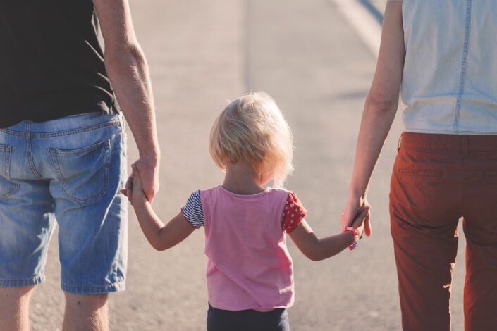 Family in casual attire walking along the road, each holding one hand of their assumed daughter. The article talks about Compulsory Family Dispute Resolution.