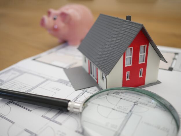 Image of a fictional house next to magnifying glass, and a piggybank. The article discusses property settlement orders related to superannuation splits.