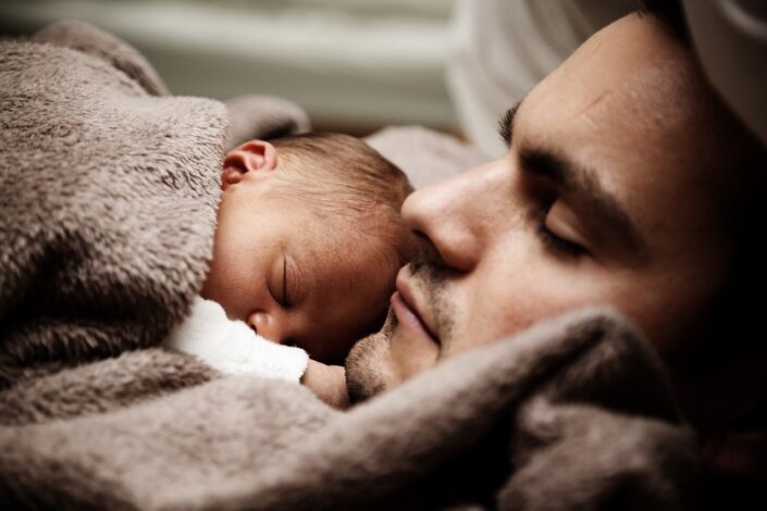 Young man asleep with his child.